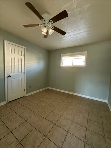 en empty room with windows and ceiling fan