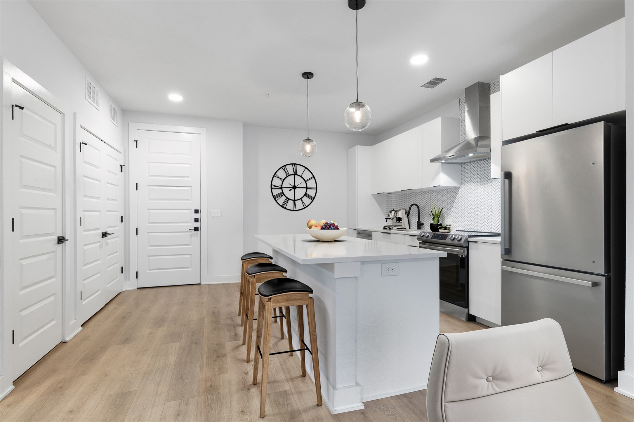 2500 Longview Street, Unit 418 Austin, TX 78705 - Photo 5 of 40 Kitchen with stainless steel appliances, white cabinets, wall chimney exhaust hood, light wood-style flooring, and recessed lighting