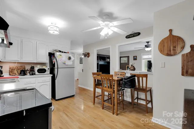 a kitchen with stainless steel appliances granite countertop a dining table chairs refrigerator and sink