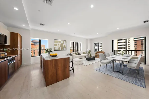 a large living room with stainless steel appliances granite countertop a couch and a large window