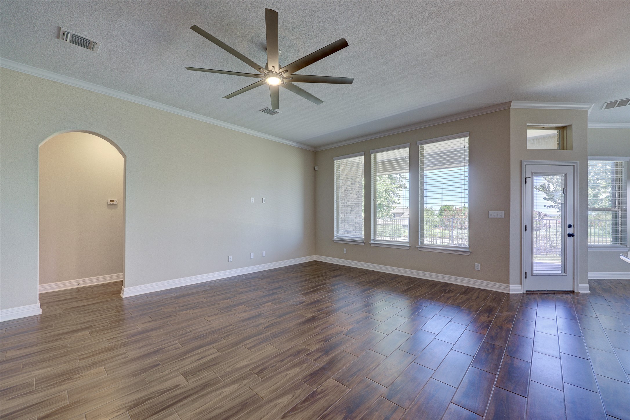 409 Betony Loop Buda, TX 78610 - Photo 7 of 38 Hardwood-style flooring and crown molding define this versatile living area, illuminated by multiple windows.