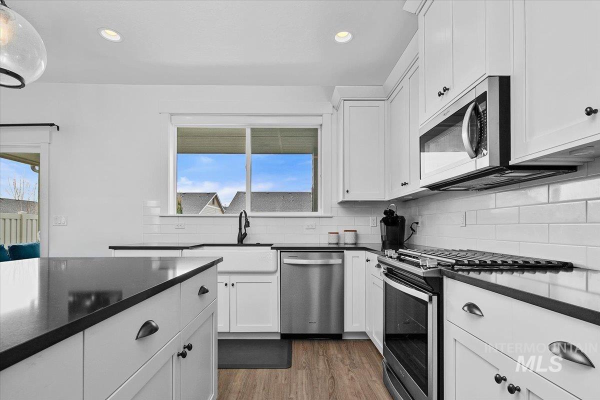 2085 North Concha Court Middleton, ID 83644 - Photo 11 of 37 Kitchen featuring stainless steel appliances, dark stone counters, dark wood-style floors, white cabinets, and recessed lighting