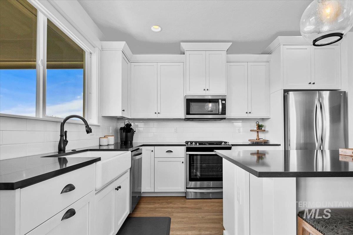 2085 North Concha Court Middleton, ID 83644 - Photo 12 of 37 Kitchen featuring stainless steel appliances, dark stone counters, white cabinetry, dark wood finished floors, and recessed lighting