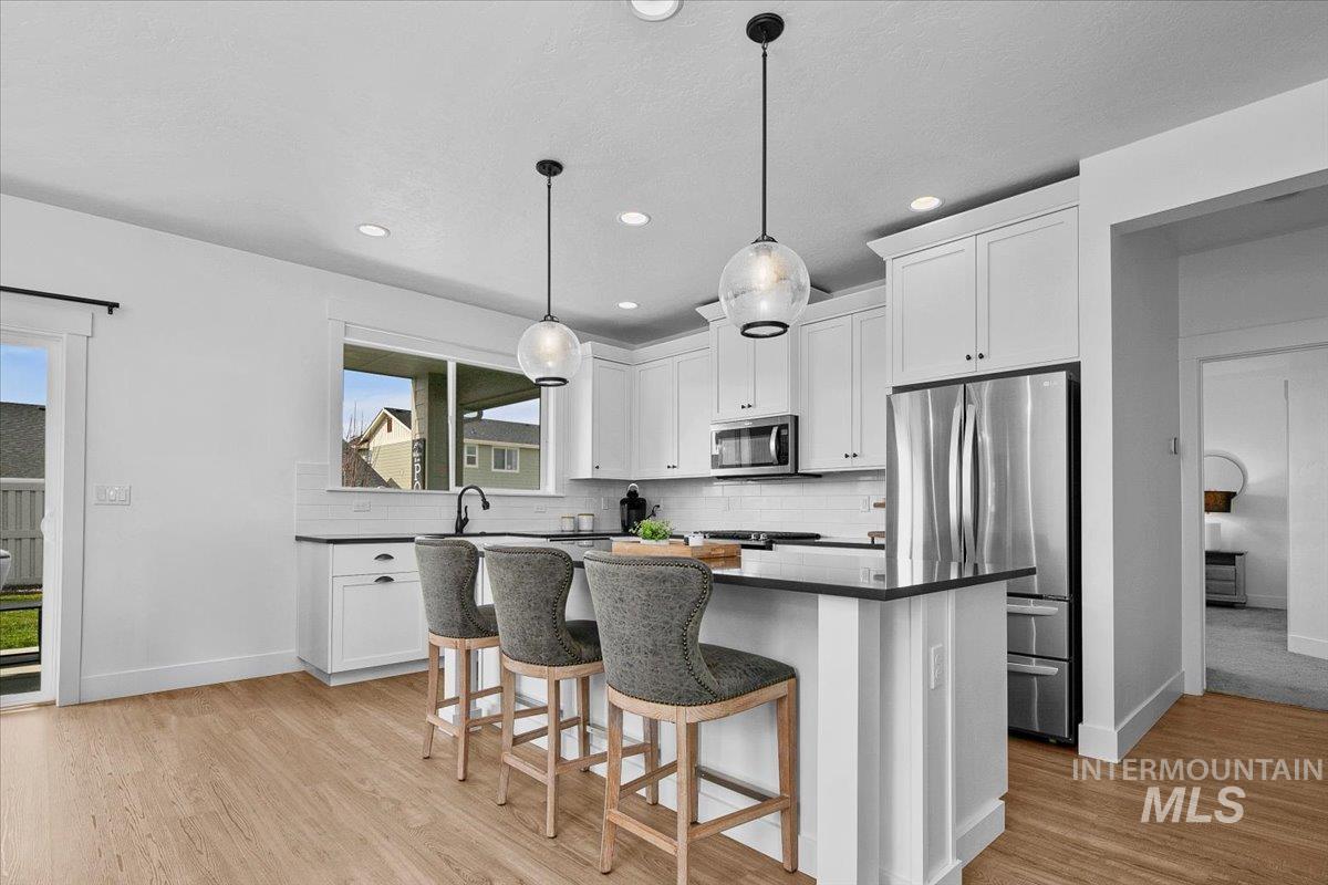 2085 North Concha Court Middleton, ID 83644 - Photo 10 of 37 Kitchen featuring white cabinets, stainless steel appliances, a kitchen breakfast bar, and light wood finished floors