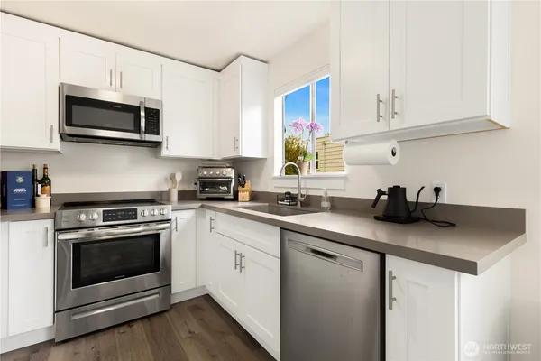 a kitchen with stainless steel appliances granite countertop a sink a stove a microwave and wooden cabinets