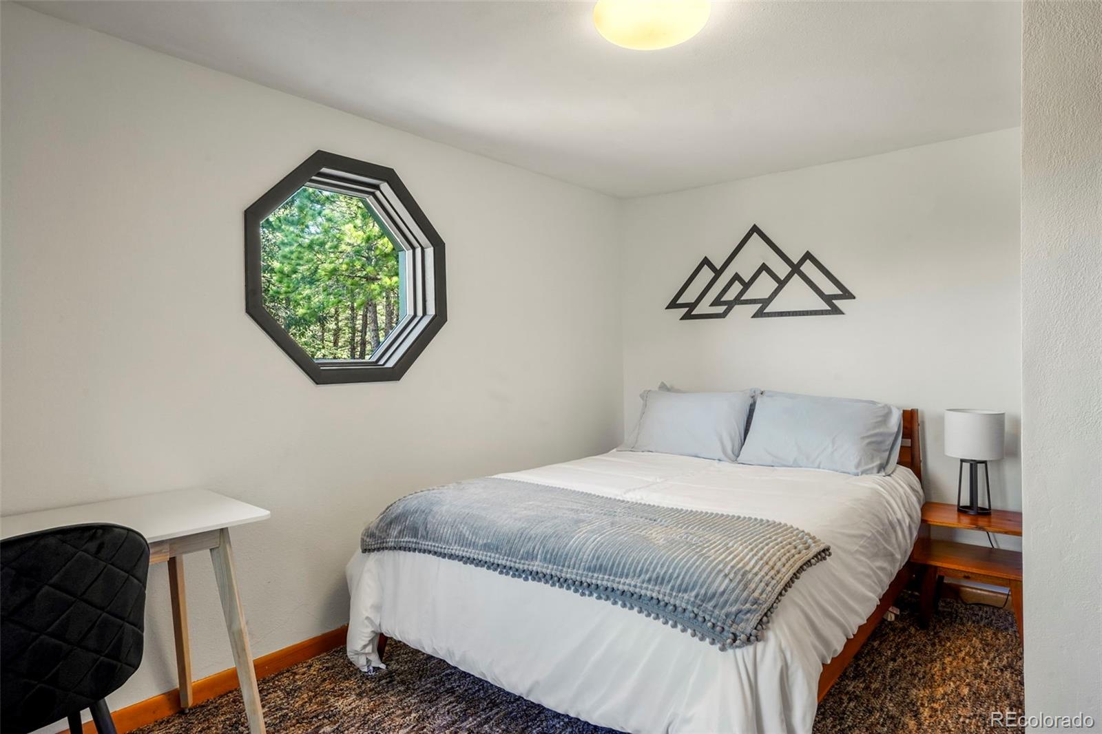 25756 Zugspitz Road Evergreen, CO 80439 - Photo 27 of 43 a bedroom with a bed and a chandelier