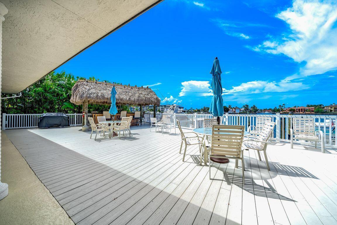3567 Commodore Circle Delray Beach, FL 33483 - Photo 59 of 76 a view of a patio with dining table and chairs with wooden floor and fence