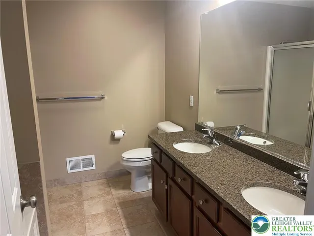 a bathroom with a granite countertop sink toilet and mirror