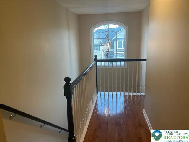 a view of a hallway with wooden floor and chandelier