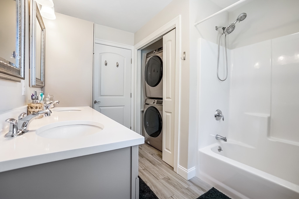 55 Plymouth Street, Unit A5 Whitman, MA 02382 - Photo 20 of 34 a bathroom with a granite countertop sink a mirror a bathtub and shower