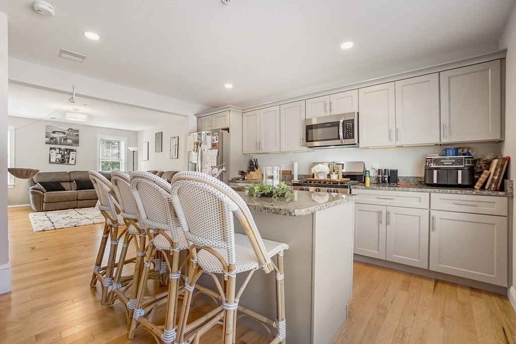 55 Plymouth Street, Unit A5 Whitman, MA 02382 - Photo 6 of 34 a kitchen with stainless steel appliances granite countertop a stove top oven a sink a refrigerator with white cabinets and wooden floor