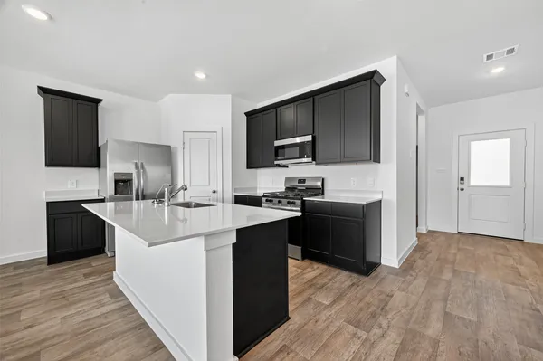 a large kitchen with stainless steel appliances a large counter top a sink and a stove