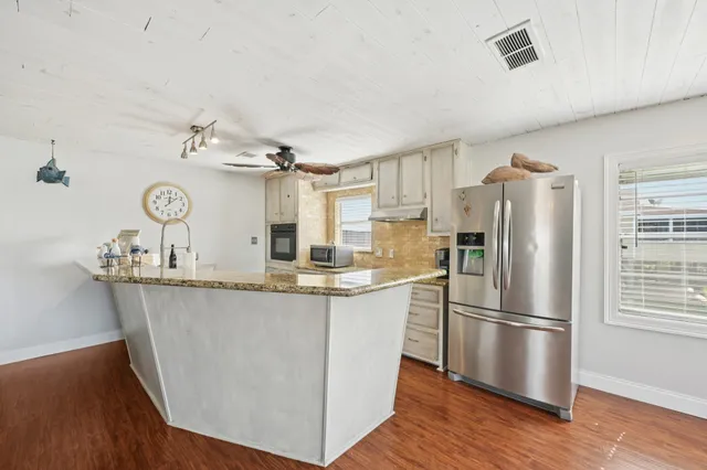 a kitchen with stainless steel appliances granite countertop a refrigerator and a stove top oven