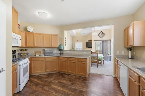 a kitchen with stainless steel appliances granite countertop a stove a sink dishwasher and a refrigerator with wooden floor