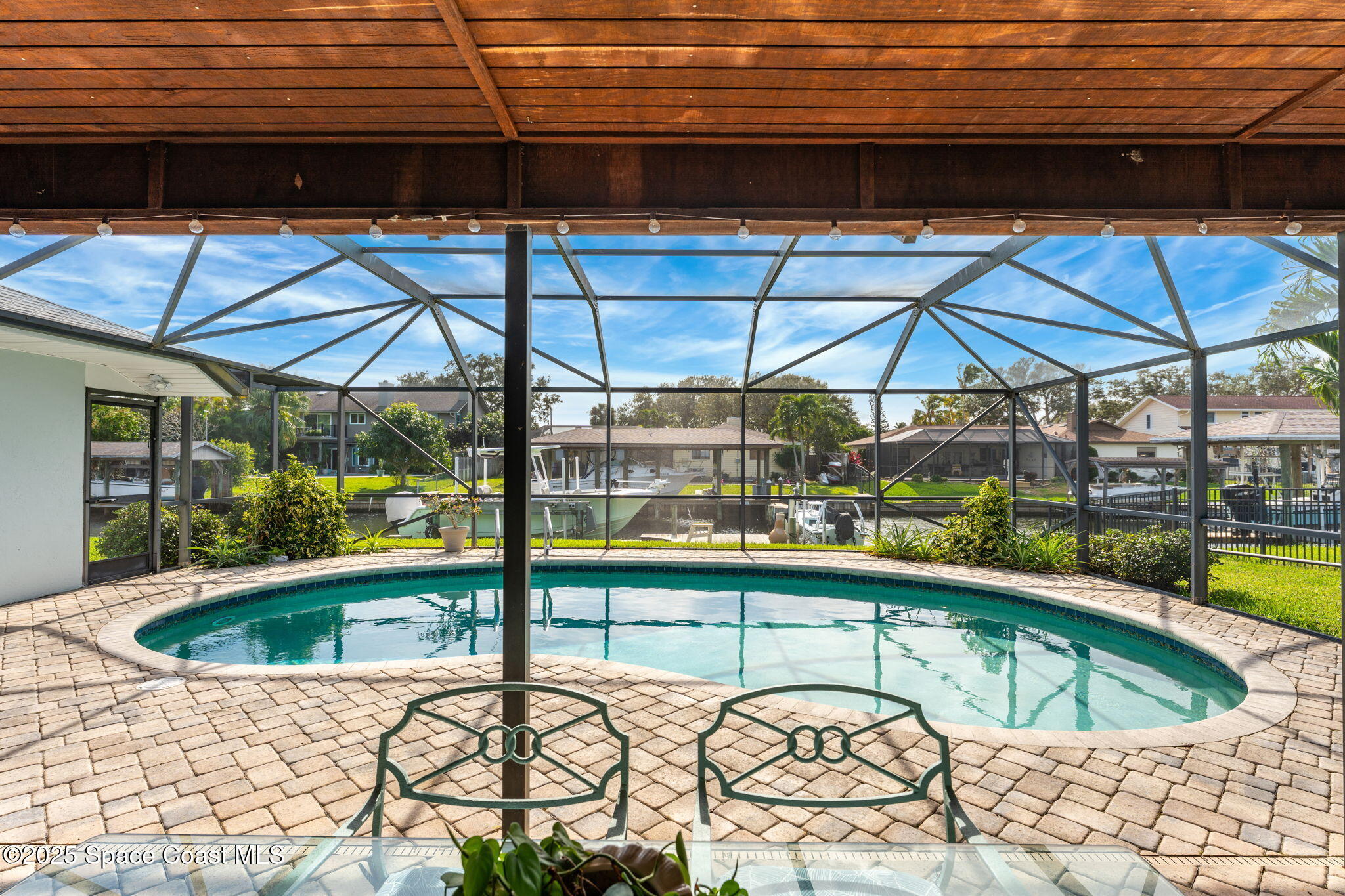 615 Mark And Randy Drive Satellite Beach, FL 32937 - Photo 7 of 40 a view of a swimming pool with a lawn chairs under an umbrella