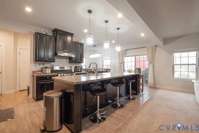 a kitchen with kitchen island granite countertop a sink counter and chairs