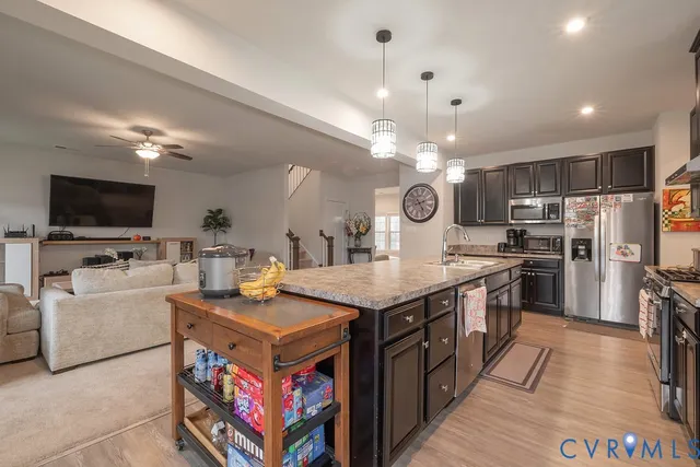 a kitchen with stainless steel appliances a stove top oven a refrigerator a kitchen island a sink and a stove