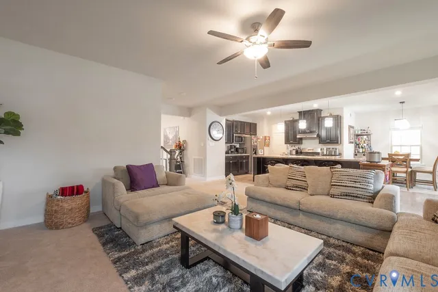 a living room with furniture kitchen view and a chandelier