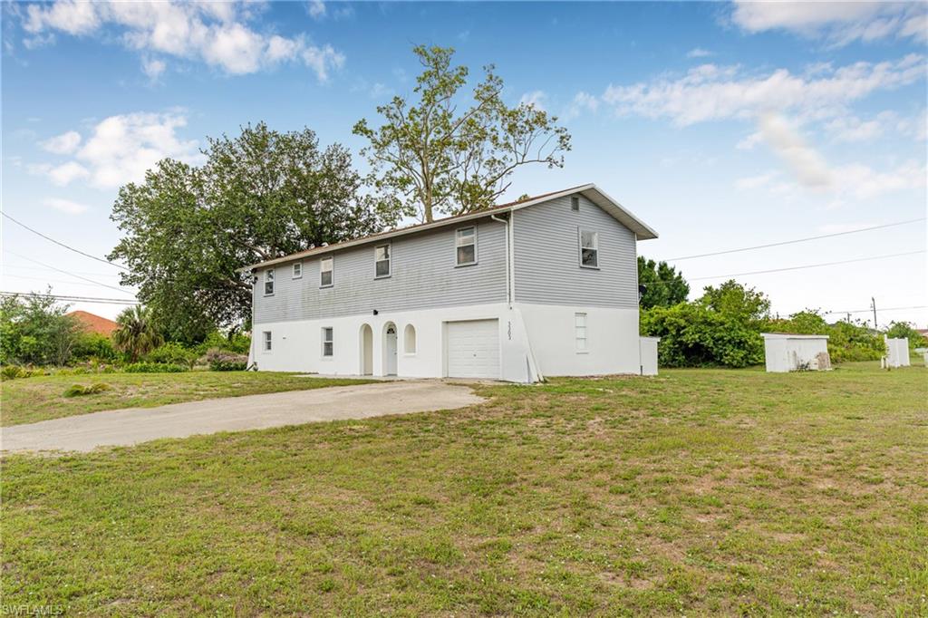 3303 6th Street Southwest Lehigh Acres, FL 33976 - Photo 3 of 23 a big white house with a yard and large trees
