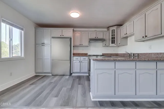 a kitchen with granite countertop white cabinets and wooden floor