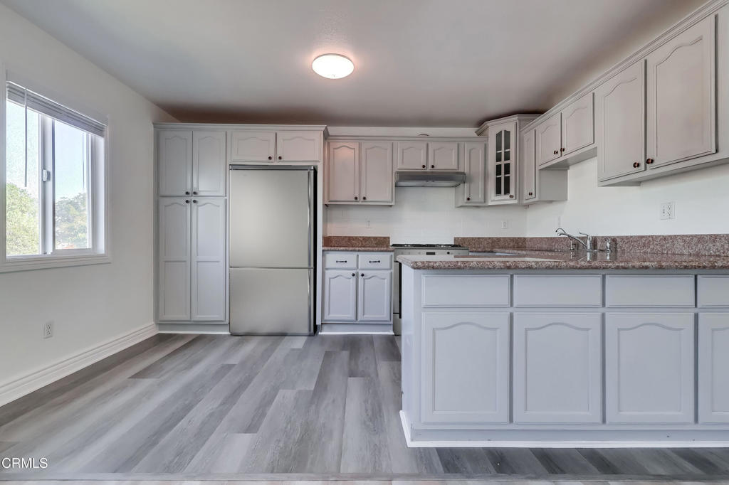 140 East 101st Street Los Angeles, CA 90003 - Photo 8 of 22 a kitchen with granite countertop white cabinets and wooden floor