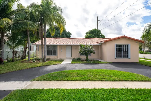 a front view of a house with a yard and potted plants