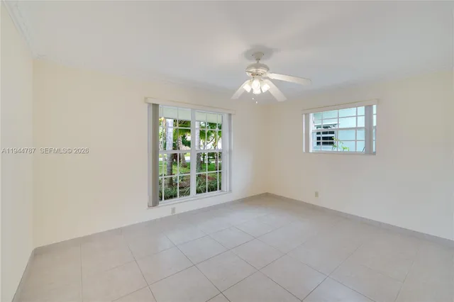 an empty room with a chandelier fan and windows