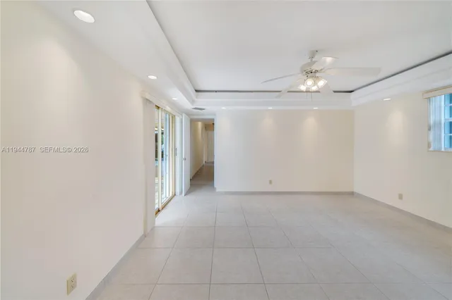 a view of a white house next to a yard with palm trees