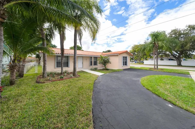 a view of a house with a yard and palm trees