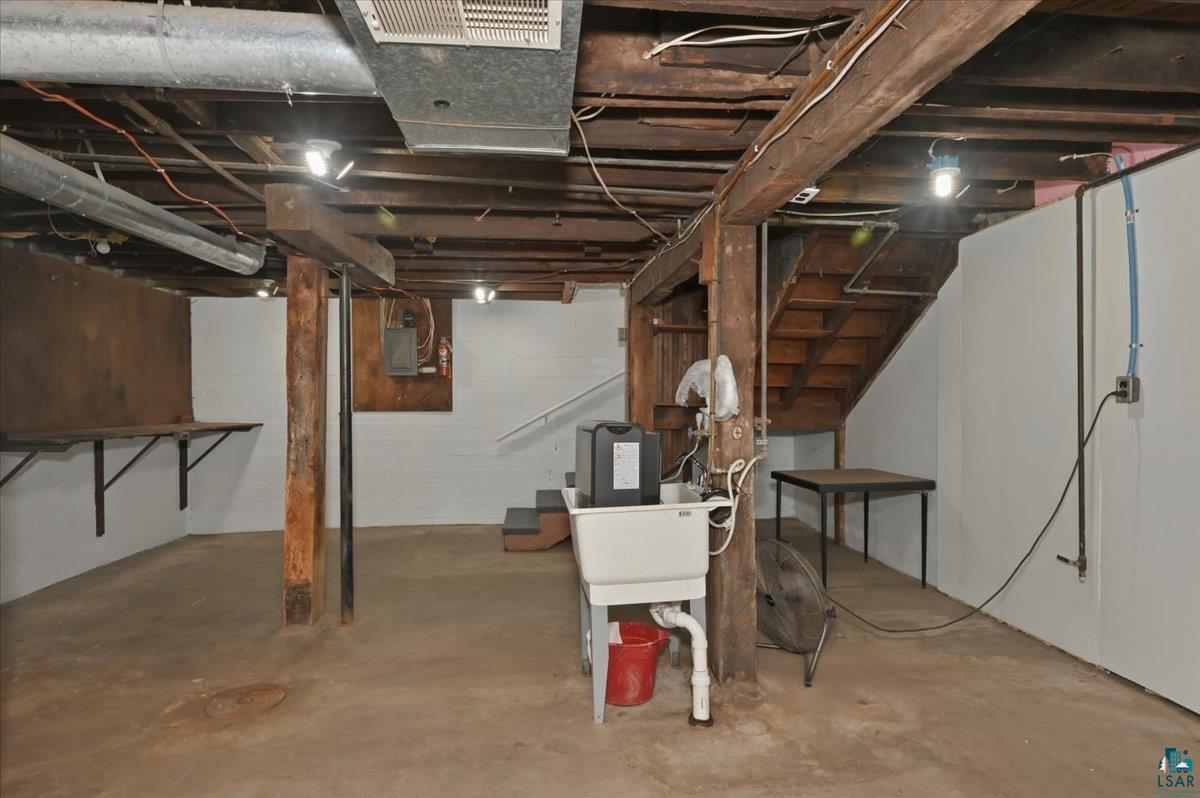5319 East 3rd Street Superior, WI 54880 - Photo 23 of 33 Unfinished basement featuring exposed wood beams, concrete flooring, and a utility sink
