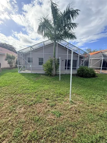 a backyard of a house with plants and large tree