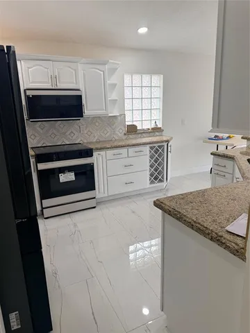 a kitchen with stainless steel appliances granite countertop a sink stove and microwave