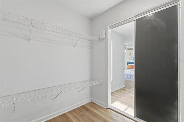 an empty room with wooden floor closet and fan