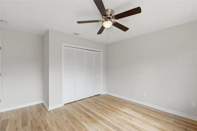 a view of empty room with wooden floor and fan