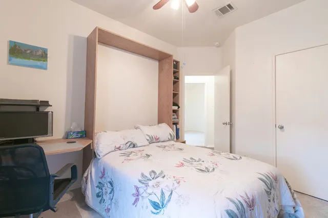 a bedroom with a bed and a computer on the desk