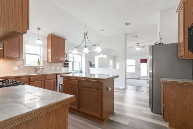 a kitchen with stainless steel appliances granite countertop a sink a stove and a wooden floors