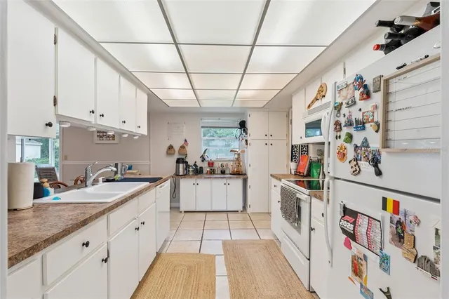 a large white kitchen with a lot of counter space and wooden floor