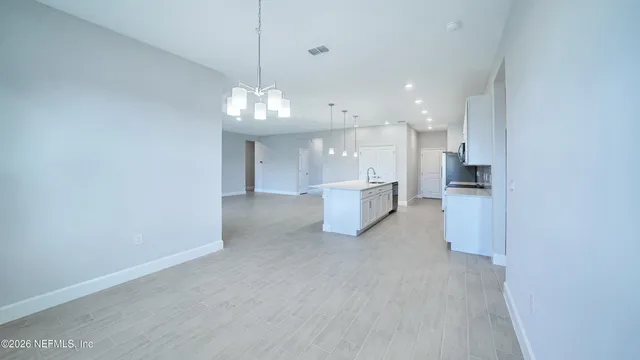 a view of kitchen with refrigerator and white cabinets