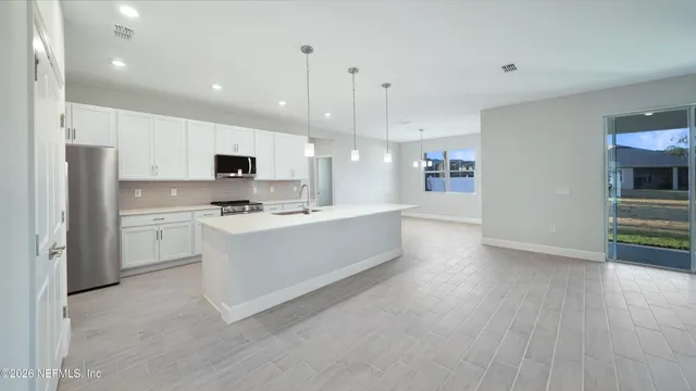 a large white kitchen with a refrigerator a stove top oven a sink and dishwasher with wooden floor