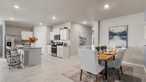 a kitchen with white cabinets and chairs