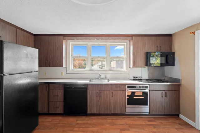 a kitchen with stainless steel appliances granite countertop hardwood floor sink stove and granite counter top