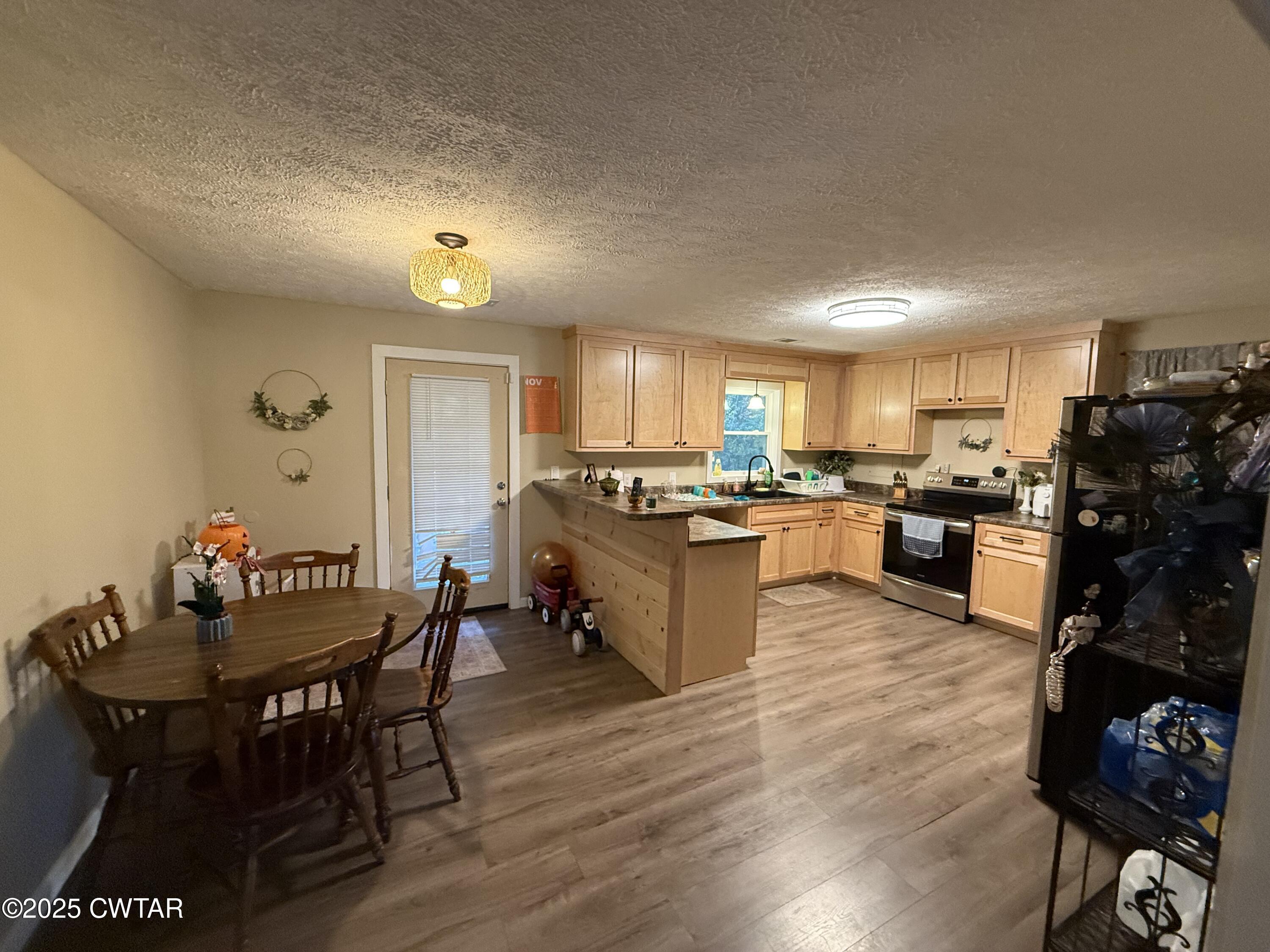152 Seavers Road Jackson, TN 38301 - Photo 3 of 11 a kitchen with stainless steel appliances granite countertop a stove a refrigerator a kitchen island a dining table and chairs with wooden floor