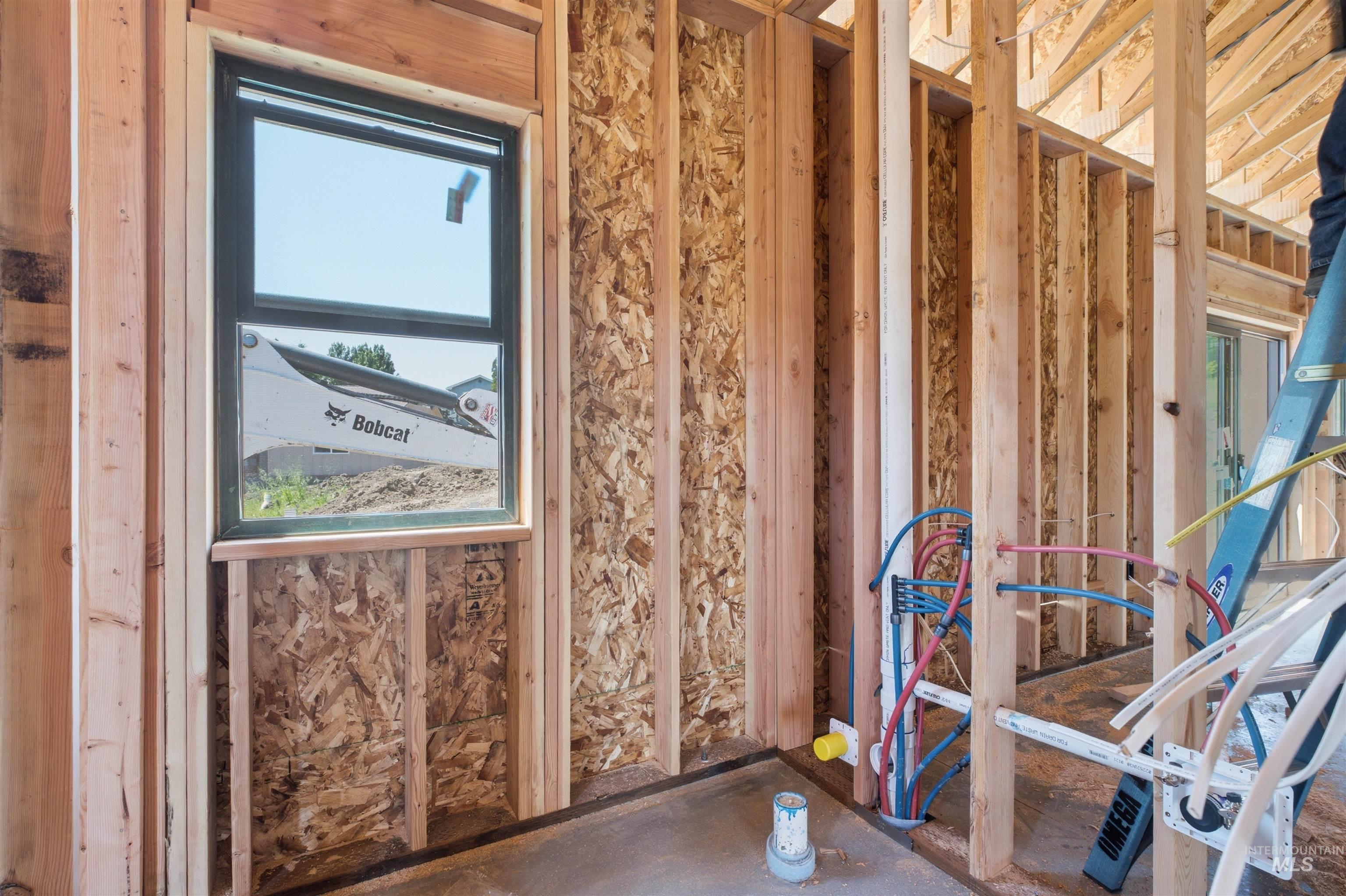 2824 Cyprus Court Moscow, ID 83843 - Photo 9 of 20 Newly framed interior space featuring a window with a dark frame, visible plumbing lines, and OSB sheathing