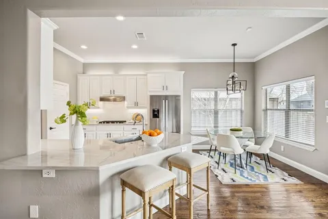 a kitchen with stainless steel appliances kitchen island granite countertop a refrigerator a stove a sink and white cabinets with wooden floor