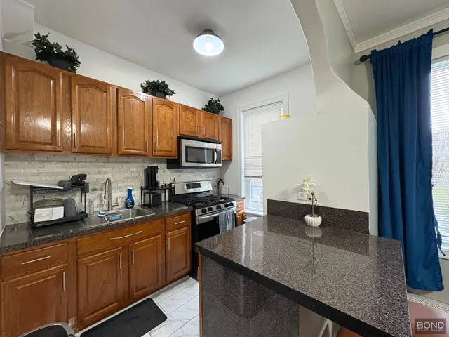 a kitchen with stainless steel appliances granite countertop a sink dishwasher stove and microwave with wooden cabinets