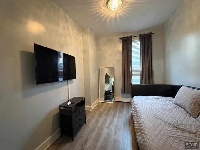 a living room with a flat screen tv a lamp and a ceiling fan