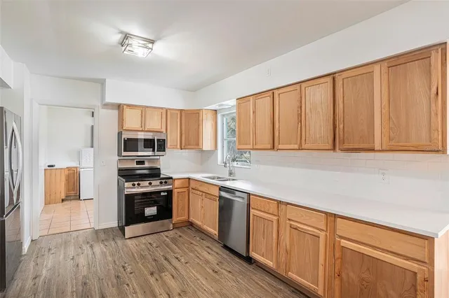 a kitchen with stainless steel appliances granite countertop a stove a sink dishwasher and a refrigerator with wooden floor