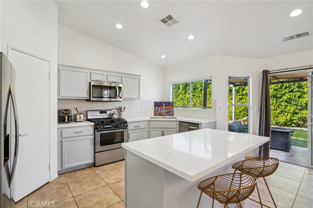 83290 Mango Walk Indio, CA 92201 - Photo 6 of 31 a kitchen with stainless steel appliances kitchen island granite countertop a stove top oven a sink a dining table and chairs