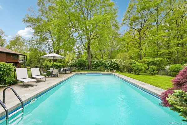 a view of pool with lawn chairs and plants