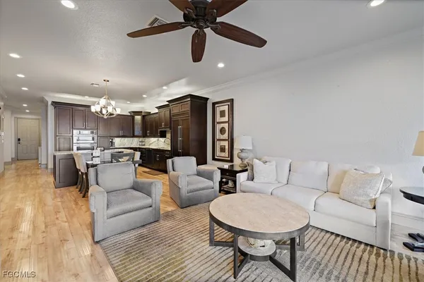 a living room with furniture kitchen view and a chandelier